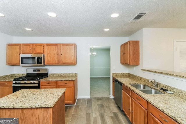 kitchen featuring visible vents, wood finished floors, a textured ceiling, a sink, and appliances with stainless steel finishes