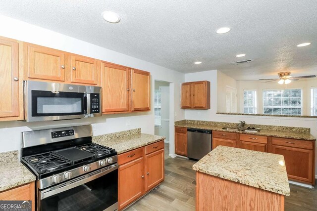 kitchen featuring a textured ceiling, wood finished floors, a sink, stainless steel appliances, and recessed lighting