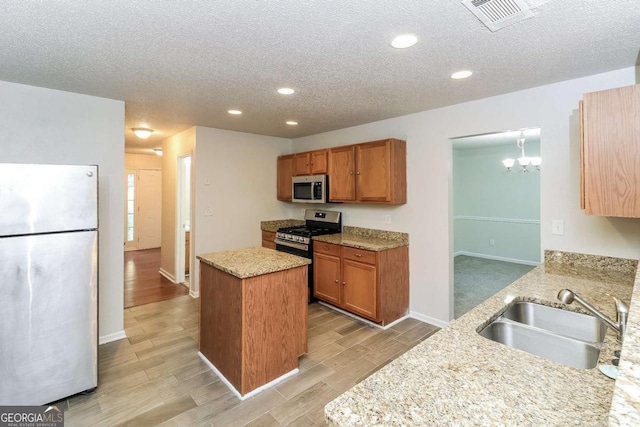 kitchen featuring visible vents, a center island, a textured ceiling, a sink, and appliances with stainless steel finishes