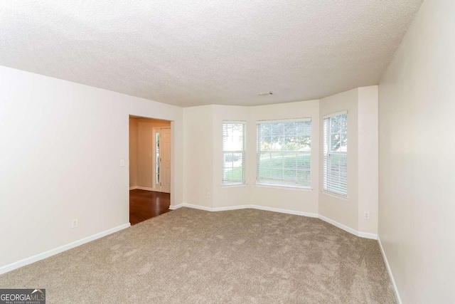 carpeted spare room featuring baseboards and a textured ceiling