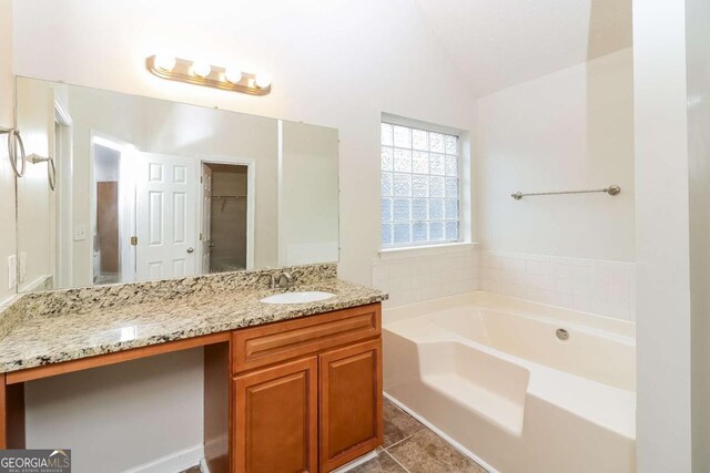 bathroom featuring vanity, lofted ceiling, tile patterned floors, a bath, and a spacious closet