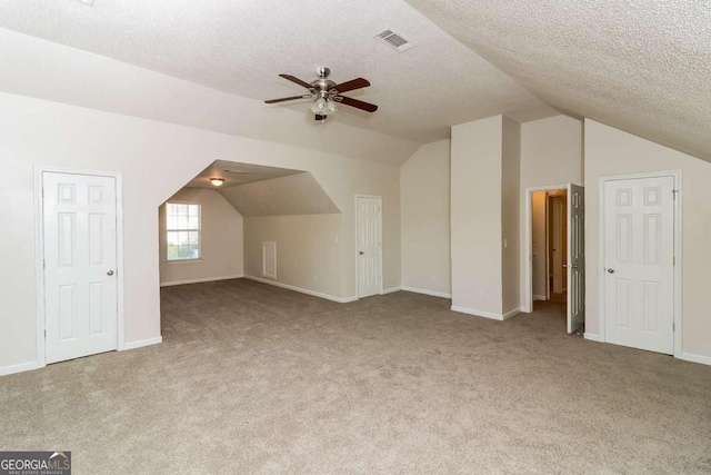 additional living space featuring carpet flooring, visible vents, a ceiling fan, baseboards, and vaulted ceiling