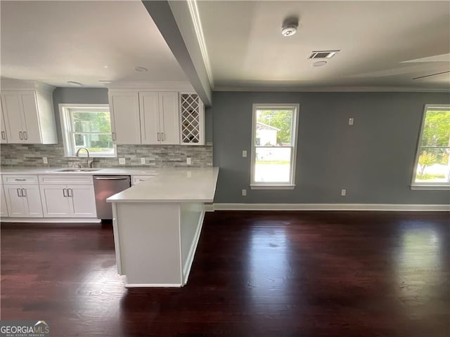 kitchen featuring stainless steel dishwasher, a peninsula, light countertops, plenty of natural light, and ornamental molding