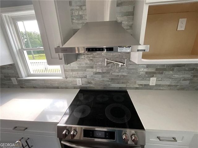 kitchen with range hood, tasteful backsplash, light countertops, electric stove, and white cabinets