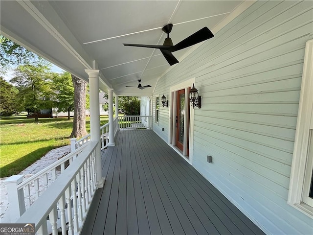 wooden deck with a porch, ceiling fan, and a lawn