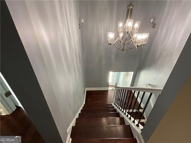 stairway with a chandelier, wood finished floors, and baseboards