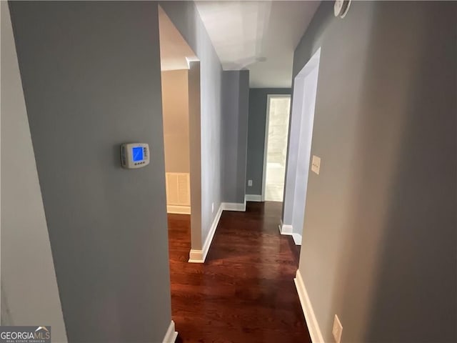 hall featuring dark wood-type flooring and baseboards