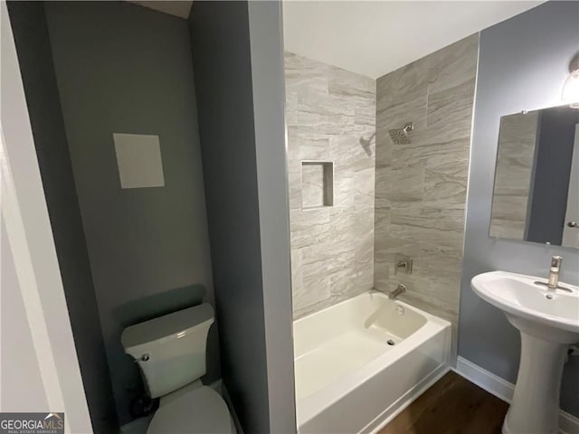 full bathroom featuring toilet, shower / washtub combination, wood finished floors, and baseboards