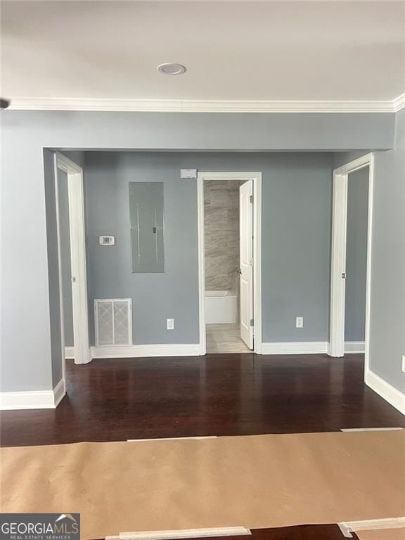 unfurnished room featuring wood finished floors, baseboards, electric panel, and ornamental molding