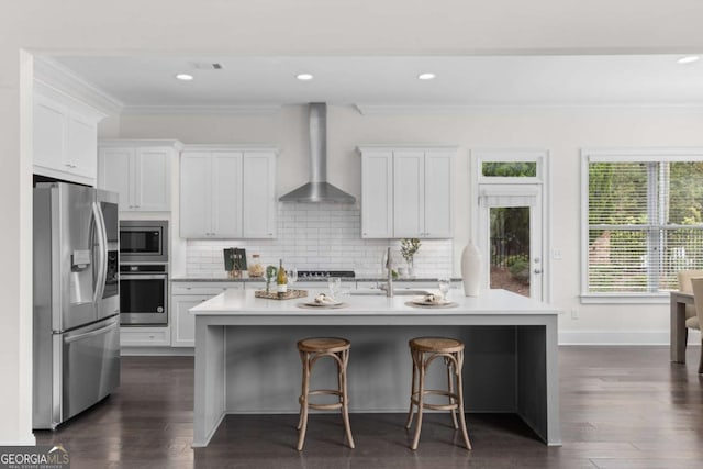 kitchen with white cabinets, light stone countertops, stainless steel appliances, and wall chimney exhaust hood