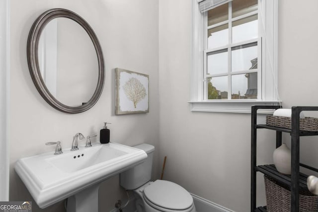 half bathroom featuring baseboards, a sink, and toilet