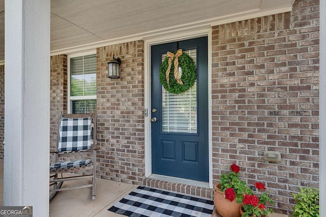property entrance with a porch and brick siding