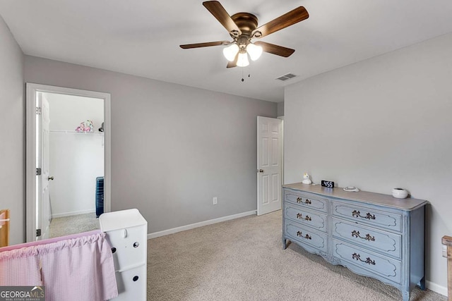 bedroom featuring ceiling fan, light colored carpet, baseboards, a spacious closet, and visible vents