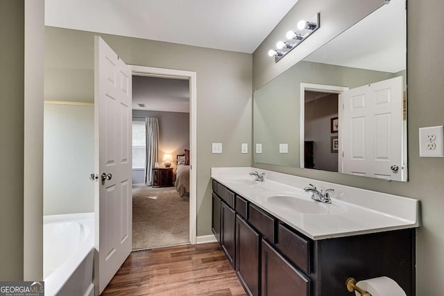full bath featuring a sink, a bath, ensuite bathroom, and wood finished floors