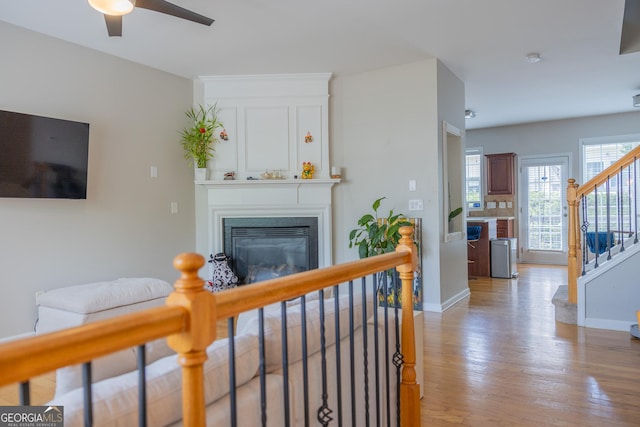 1306 Thornborough Dr Unit 1306, Alpharetta, GA 30004 - living room with ceiling fan, light wood-type flooring, stairway, a glass covered fireplace, and baseboards