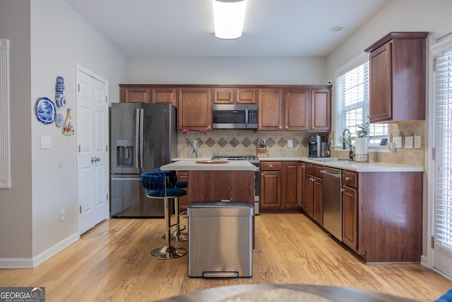 1306 Thornborough Dr Unit 1306, Alpharetta, GA 30004 - kitchen with appliances with stainless steel finishes, a sink, a breakfast bar area, light countertops, and light wood-type flooring