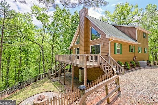 view of front facade featuring a chimney, a deck, fence private yard, a fire pit, and stairs