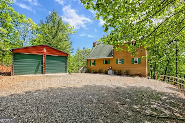 view of side of property featuring fence, a detached garage, an outdoor structure, and a chimney