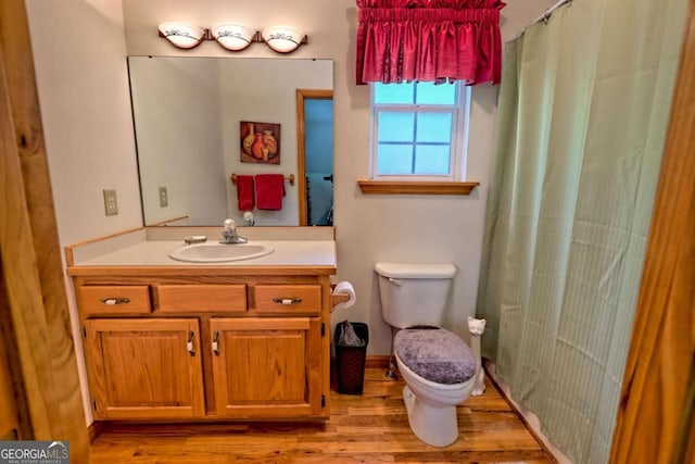 full bath with vanity, wood finished floors, toilet, and curtained shower