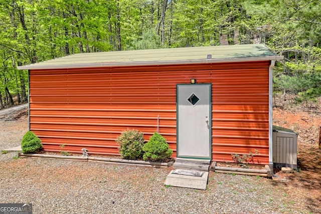 view of outbuilding featuring a view of trees and an outdoor structure