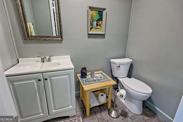 half bath featuring toilet, baseboards, and vanity