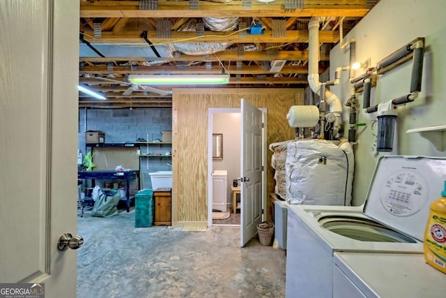 unfinished below grade area with washing machine and clothes dryer and concrete block wall