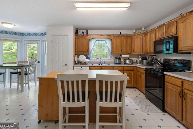 569 Hale Mountain Ct, Hiram, GA 30141 - kitchen with light countertops, light floors, a center island, and black appliances