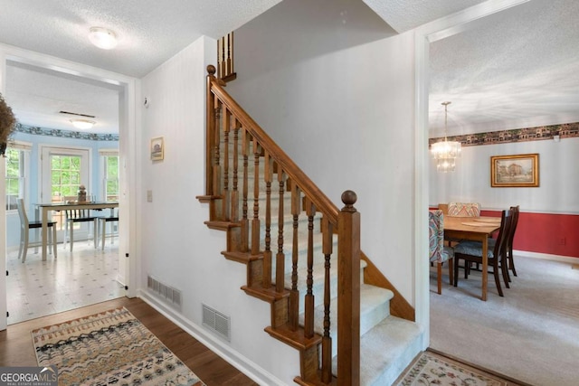 569 Hale Mountain Ct, Hiram, GA 30141 - stairs featuring a chandelier, a textured ceiling, and visible vents
