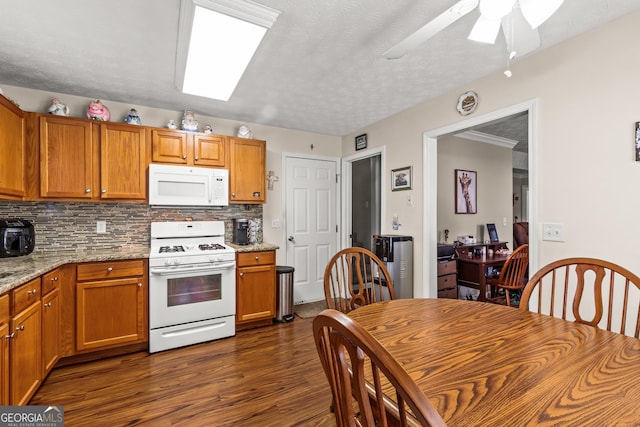 kitchen featuring a ceiling fan, dark wood-style flooring, backsplash, brown cabinets, and white appliances
