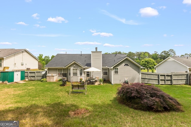 back of house featuring a lawn, a patio, a chimney, and a fenced backyard