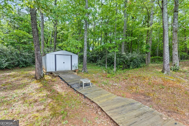 view of yard with a forest view, an outbuilding, and a storage unit