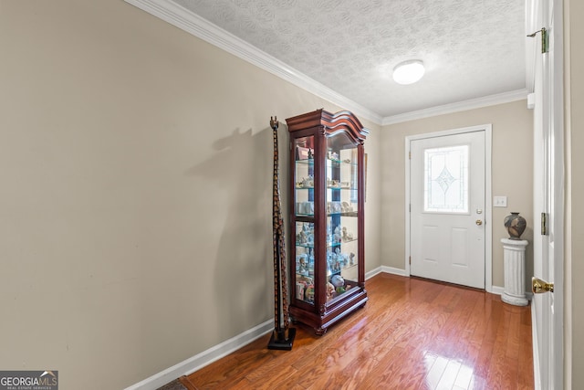 entrance foyer with baseboards, a textured ceiling, crown molding, and wood finished floors