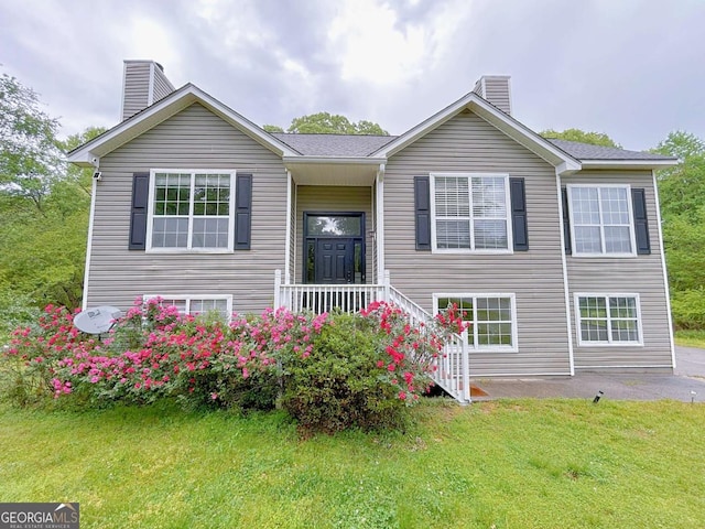 split foyer home with a chimney and a front lawn