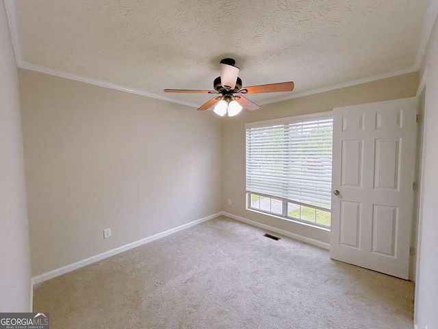 spare room with crown molding, light carpet, a ceiling fan, baseboards, and visible vents