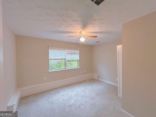 empty room with baseboards, ceiling fan, visible vents, and light colored carpet