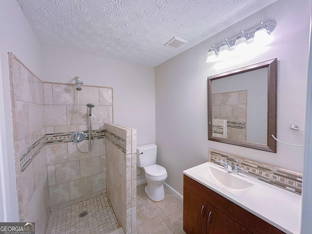 full bath with vanity, toilet, tiled shower, and visible vents