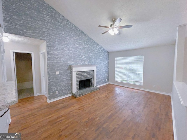 unfurnished living room with wood finished floors, a ceiling fan, lofted ceiling, and a fireplace