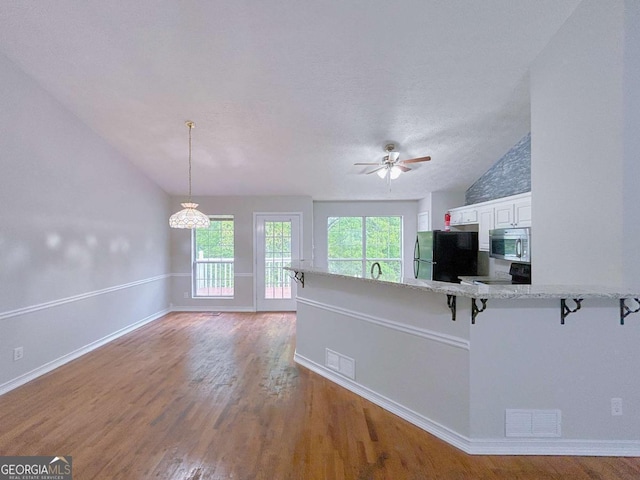 kitchen with a kitchen breakfast bar, black appliances, lofted ceiling, and visible vents
