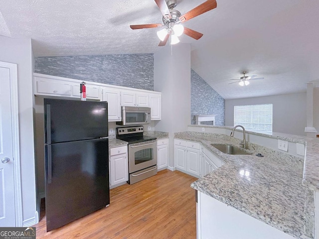kitchen with a sink, ceiling fan, vaulted ceiling, and stainless steel appliances
