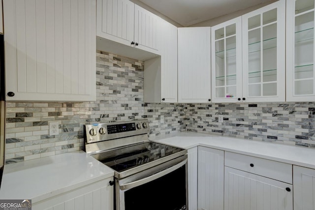kitchen with glass insert cabinets, light countertops, white cabinets, tasteful backsplash, and stainless steel range with electric cooktop