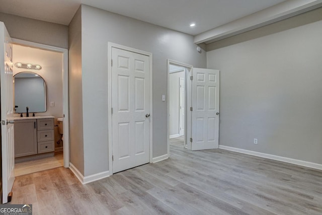 unfurnished bedroom featuring recessed lighting, baseboards, light wood-type flooring, and a sink