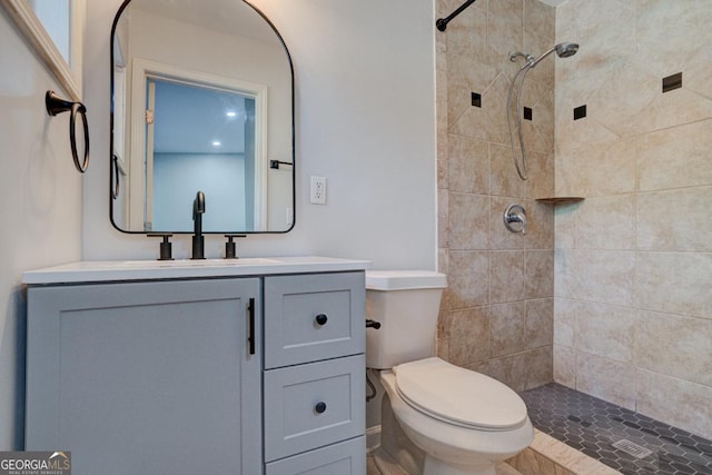 bathroom featuring toilet, tiled shower, and vanity