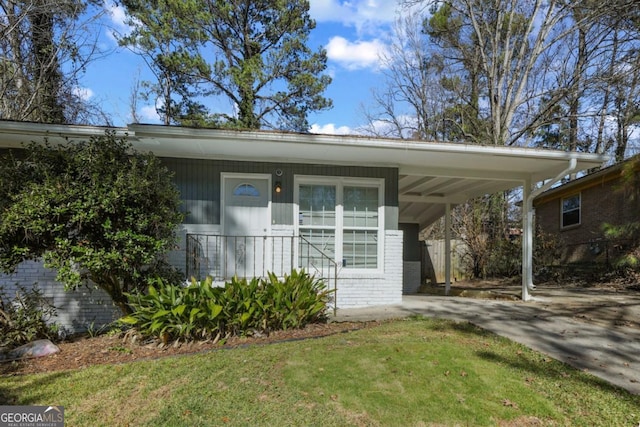 view of front of property with an attached carport, driveway, a front lawn, and brick siding