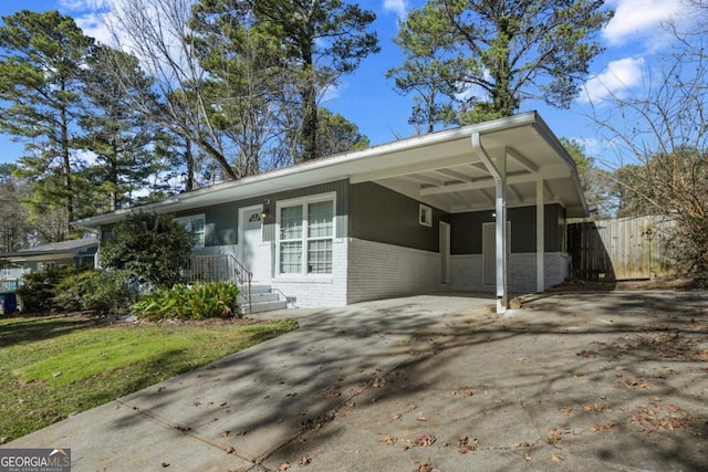 ranch-style home featuring driveway, a front yard, brick siding, fence, and an attached carport