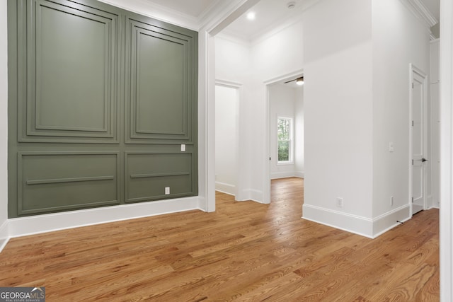 empty room featuring crown molding, baseboards, and light wood-style floors