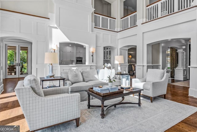 living area featuring arched walkways, a decorative wall, ornate columns, and a towering ceiling