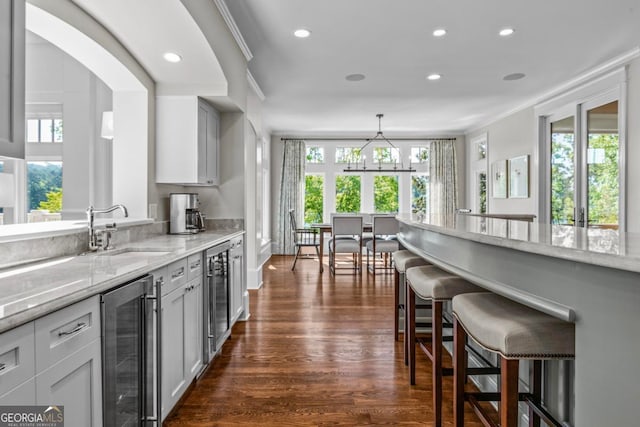 kitchen featuring beverage cooler, a kitchen breakfast bar, a healthy amount of sunlight, and a sink