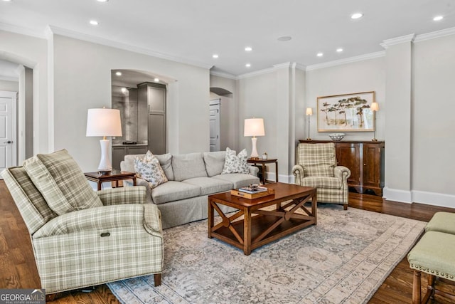 living area featuring crown molding, arched walkways, recessed lighting, baseboards, and wood finished floors