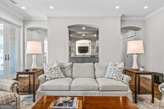 living area with arched walkways, ornamental molding, recessed lighting, and wood finished floors
