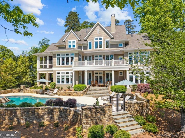 back of house with a patio, a chimney, a balcony, and an outdoor pool
